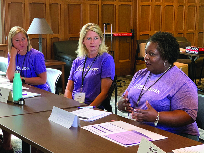 three women sit at a table, one woman talking